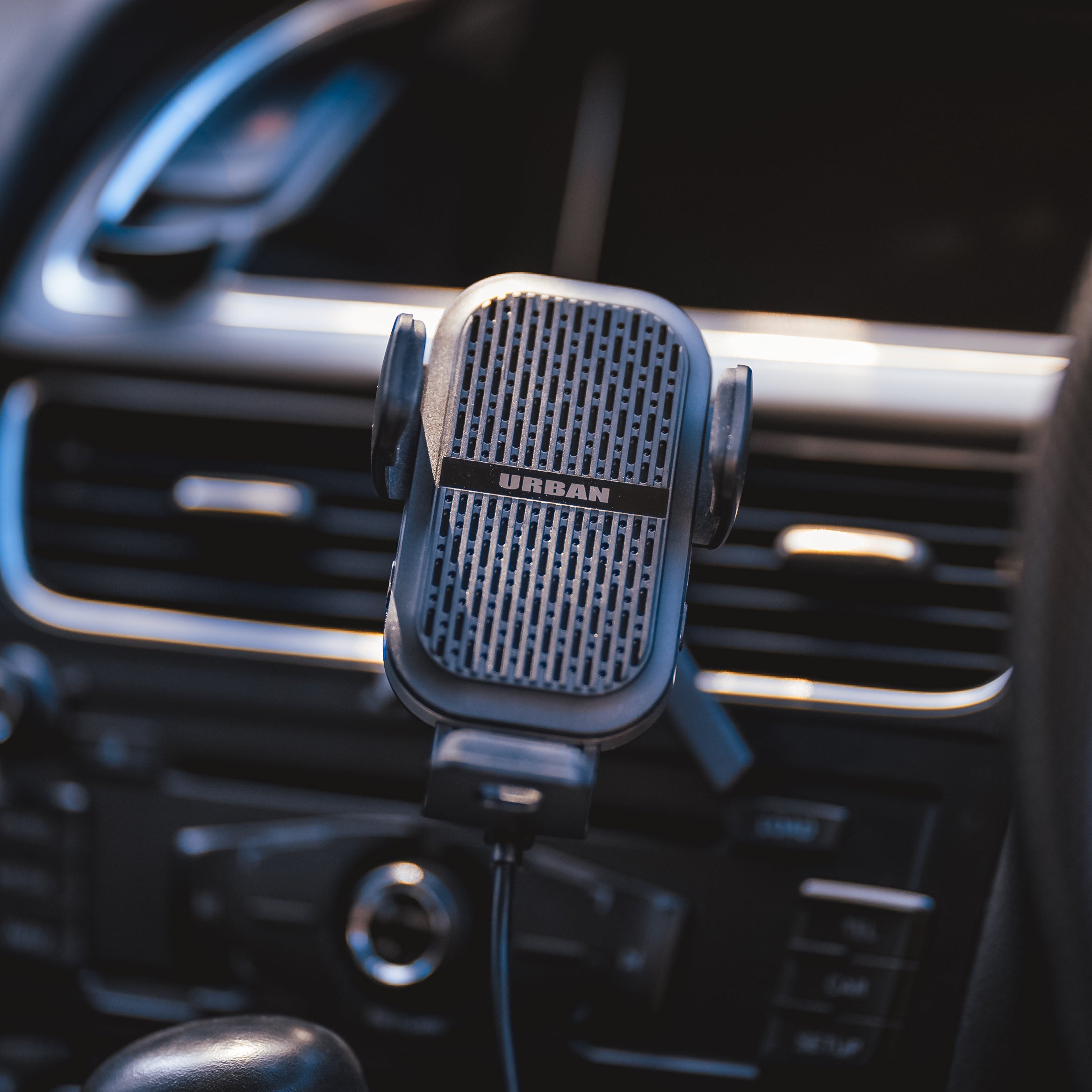 A Auto15 Pro Cooling Wireless Car Charger Kit branded "Urban" mounted on an auto-opening clamp on a car dashboard, with soft focus on the car's interior in the background.